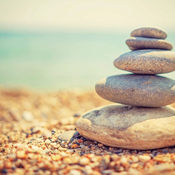 Stones pyramid on pebble beach symbolizing stability, zen, harmony, balance. Tropical sea beach. Vacation concept